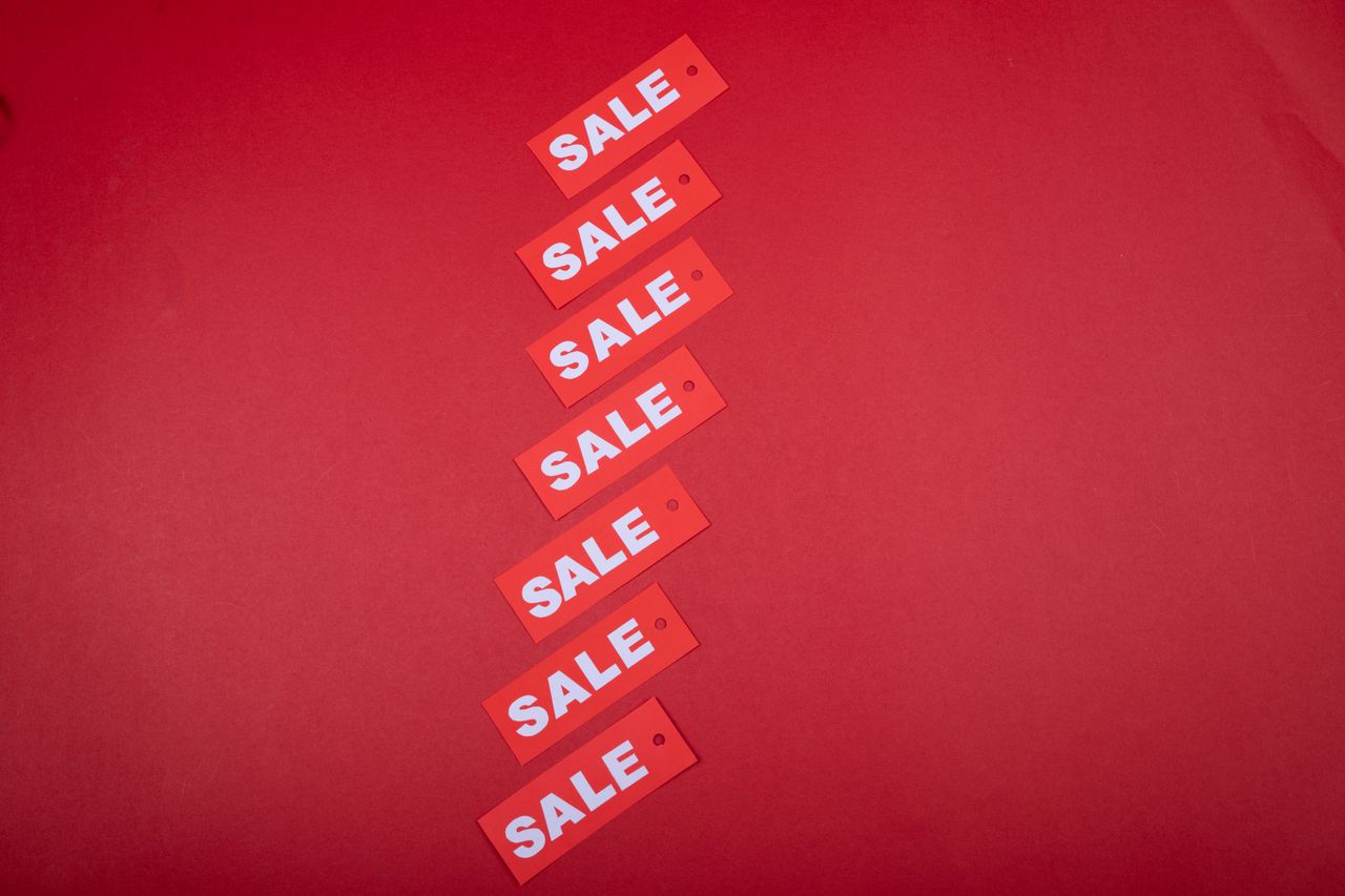 Vue de dessus d’étiquettes de soldes rouges disposées sur un fond rouge éclatant, destinées à un usage commercial.
