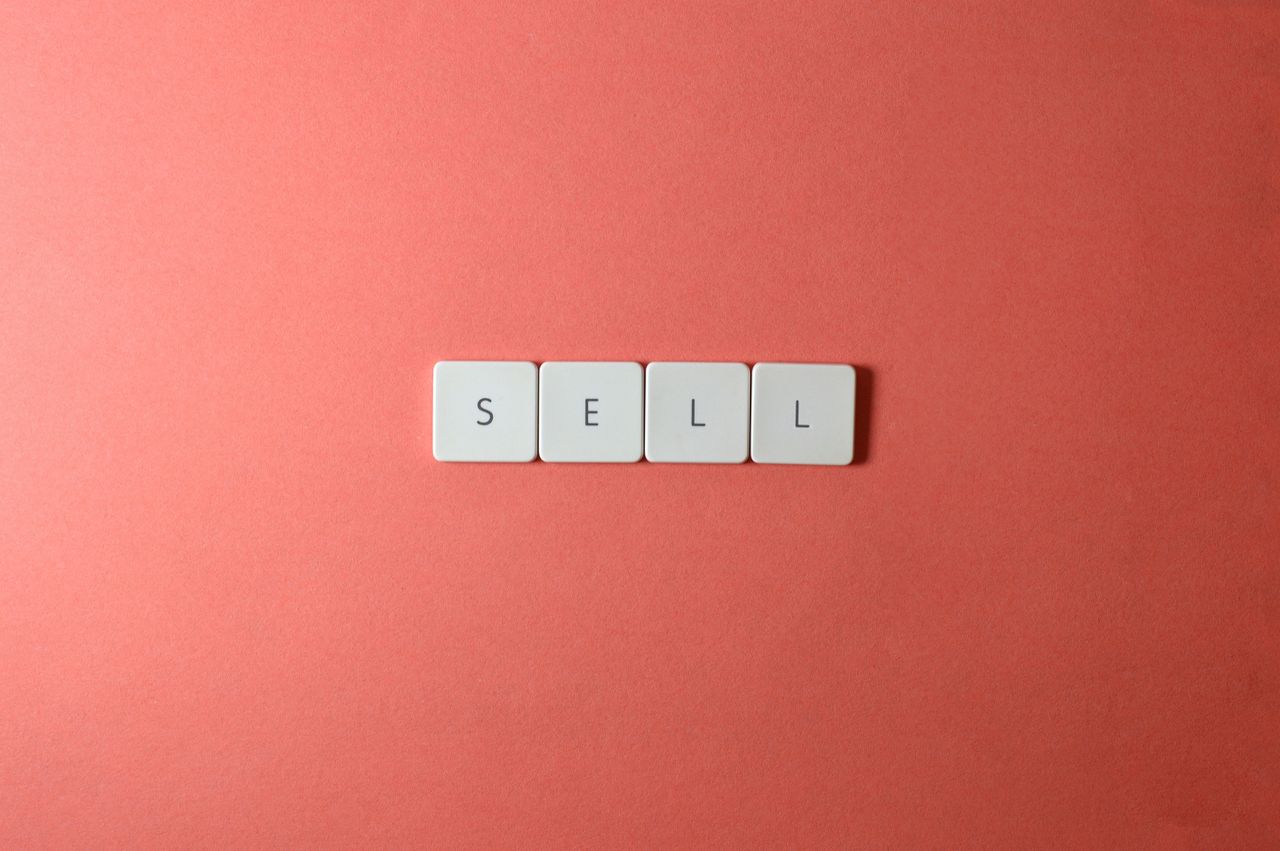 Close-up view of keyboard keys spelling sell against a red background, in a minimalist style.